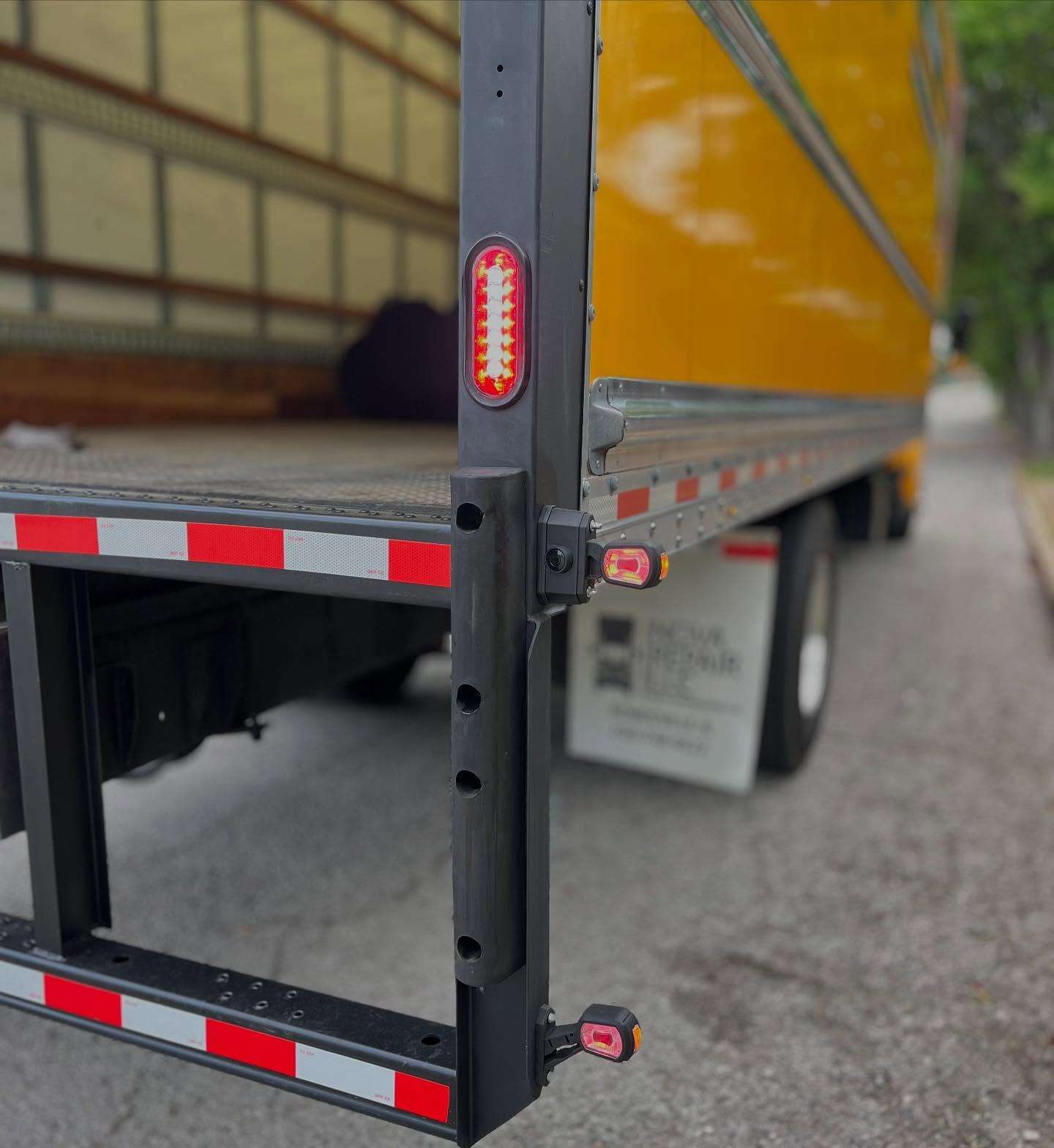Close-up of the rear of a box truck trailer with roadlites LED reverse motion sensor lights installed and red LED outline marker lights installed.