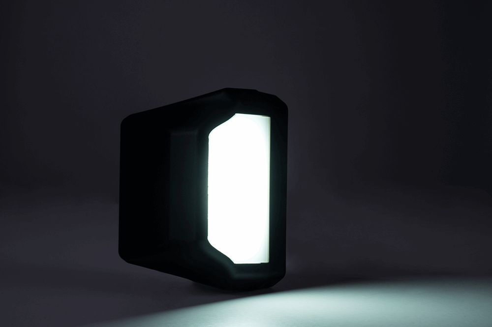 Black rectangular license plate light emitting light on a black background.