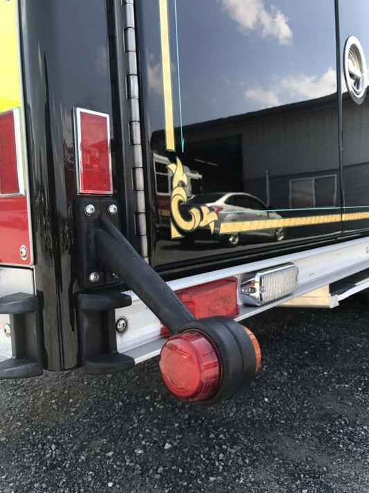 Round red lollipop-style end outline marker light on a black rubber flexible stalk at the rear corner of a fire truck.