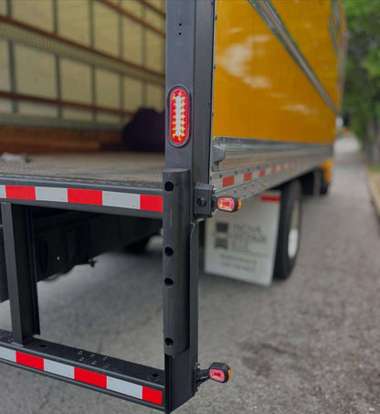 Close-up of the rear of a box truck trailer with roadlites LED reverse motion sensor lights installed and red LED outline marker lights installed.
