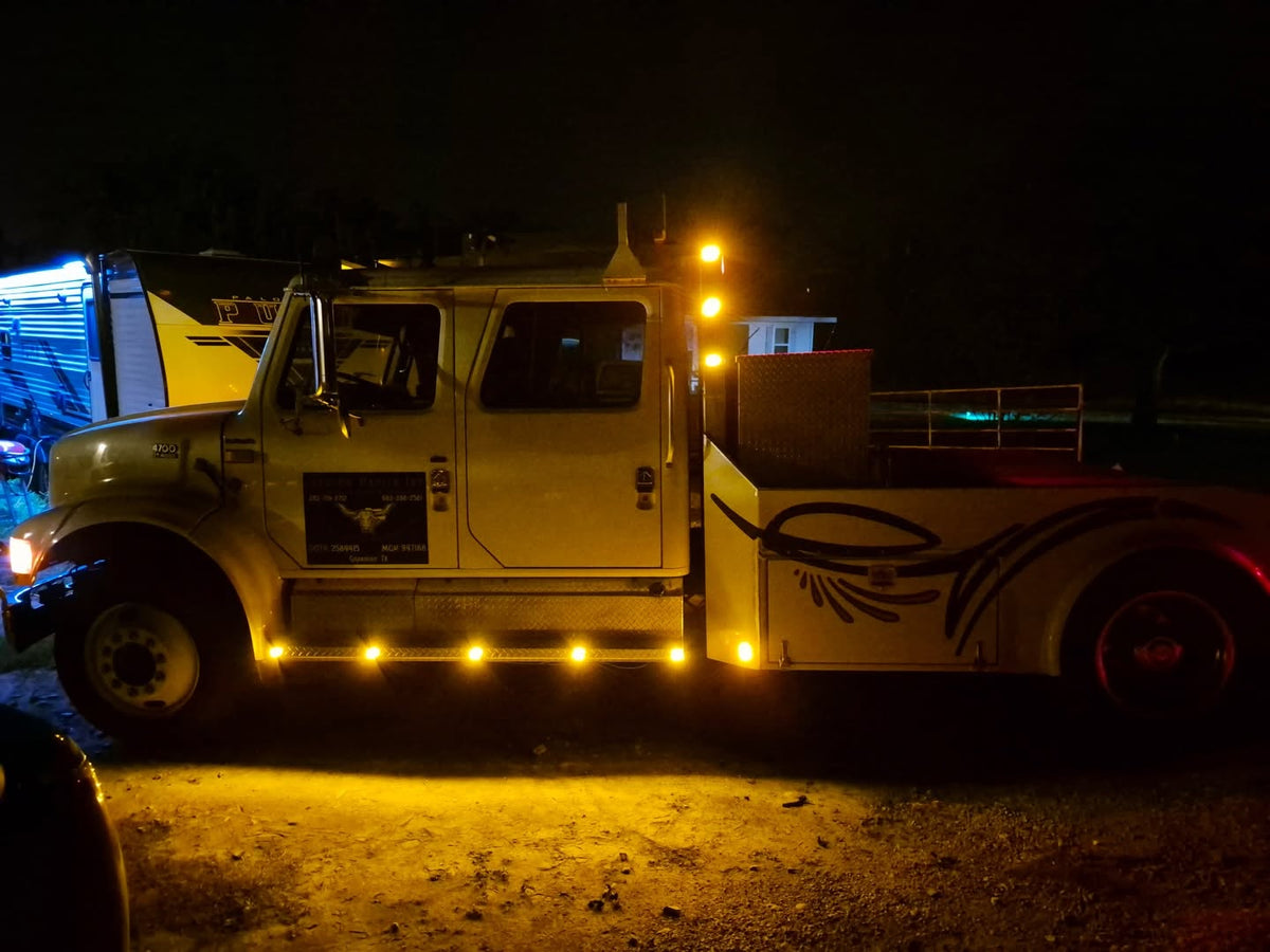 White Tow Truck at night lit up with RoadLites amber marker lights.