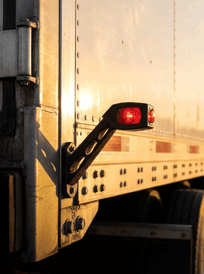 Close-up of a RoadLites trailer side outline marker light LD 518 with a red illuminated lens, mounted on the side of a trailer.