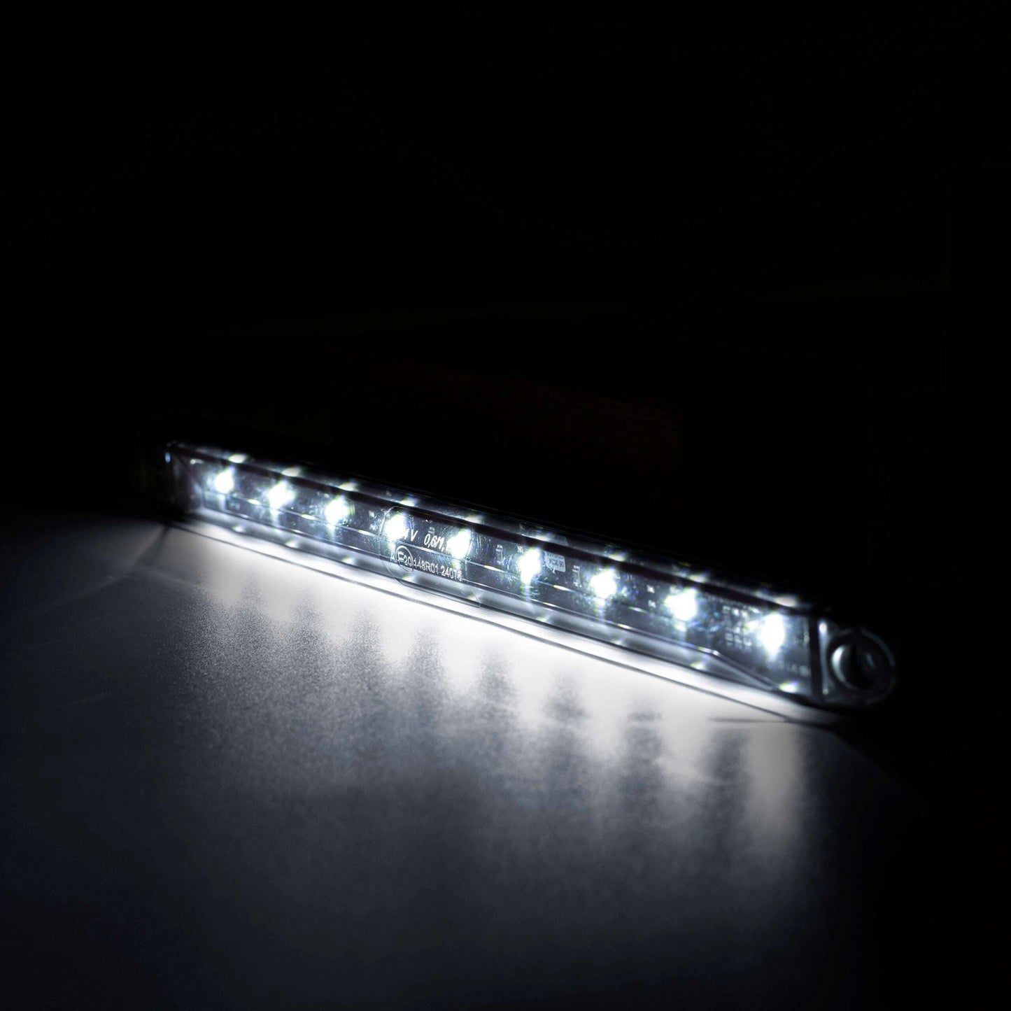 LED light bar emitting a bright white light on a dark background.